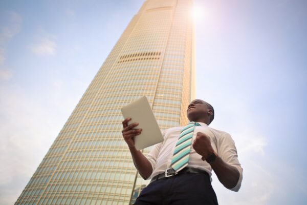 The Importance of Developing a Knowledge Management Strategy for Business Success A professional man with a tablet, focused on knowledge management strategy near a tall skyscraper.